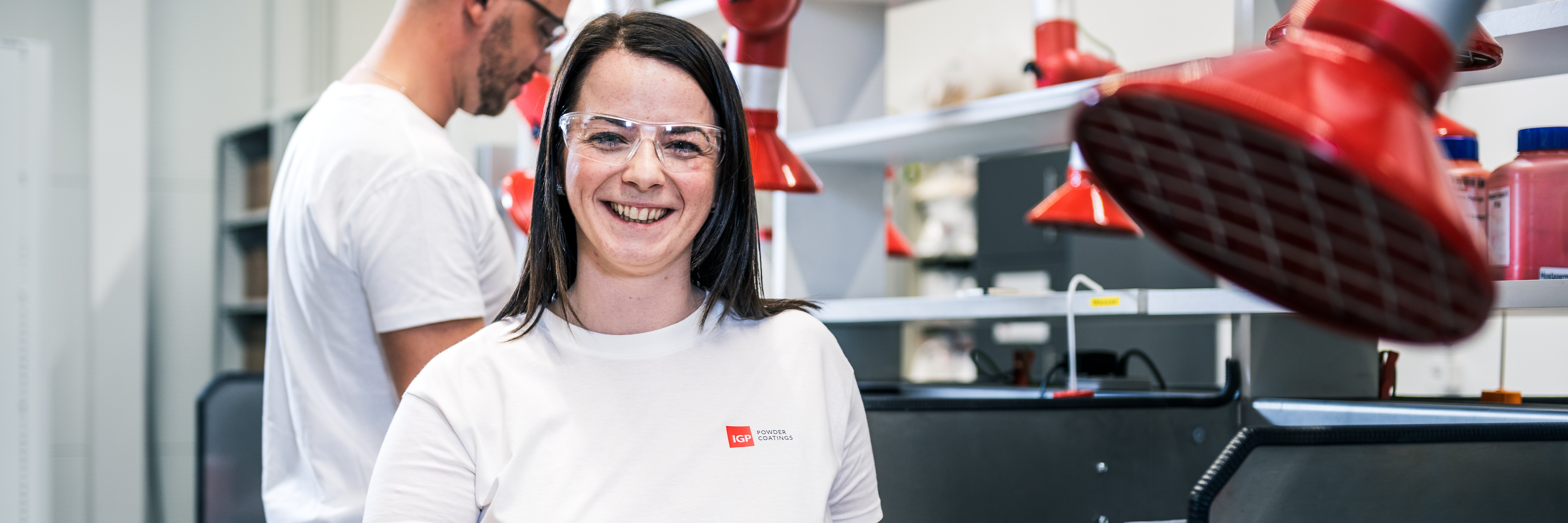 Arbeitsumfeld: Mitarbeiterin Technologie | © IGP Pulvertechnik AG Mitarbeiterin der IGP Pulvertechnik AG zeigt Rohstoff für Pulverlacke | © IGP Pulvertechnik AG