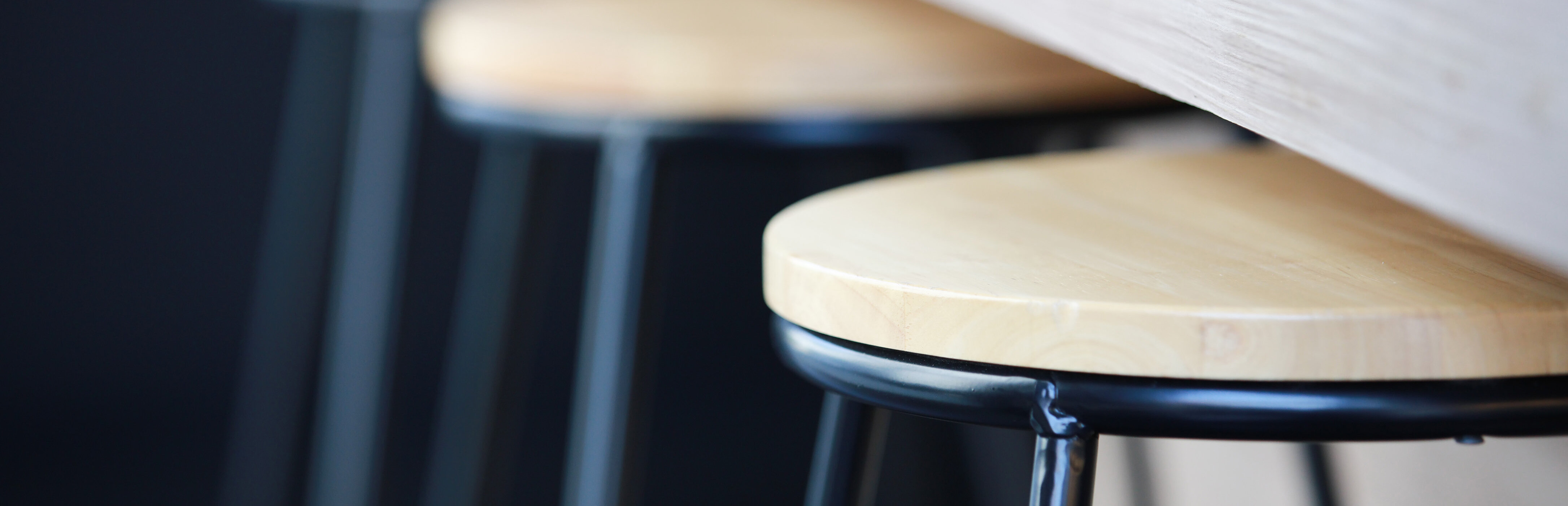 Nahaufnahme von Barhockern und Tisch in Holzoptik. Oberflächen sind mit Pulverlack beschichtet. | © Shutterstock