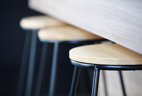 Nahaufnahme von Barhockern und Tisch in Holzoptik. Oberflächen sind mit Pulverlack beschichtet. | © Shutterstock